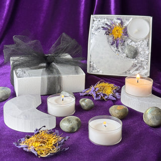 Moon Bath Full Moon Ritual Kit: open box with selenite crescent, blue lotus, labradorite and tealight beside the tied gift box on purple velvet