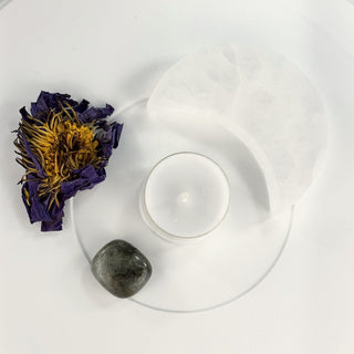 Moon Bath kit contents from above on white: selenite crescent, tealight, dried blue lotus and a labradorite stone